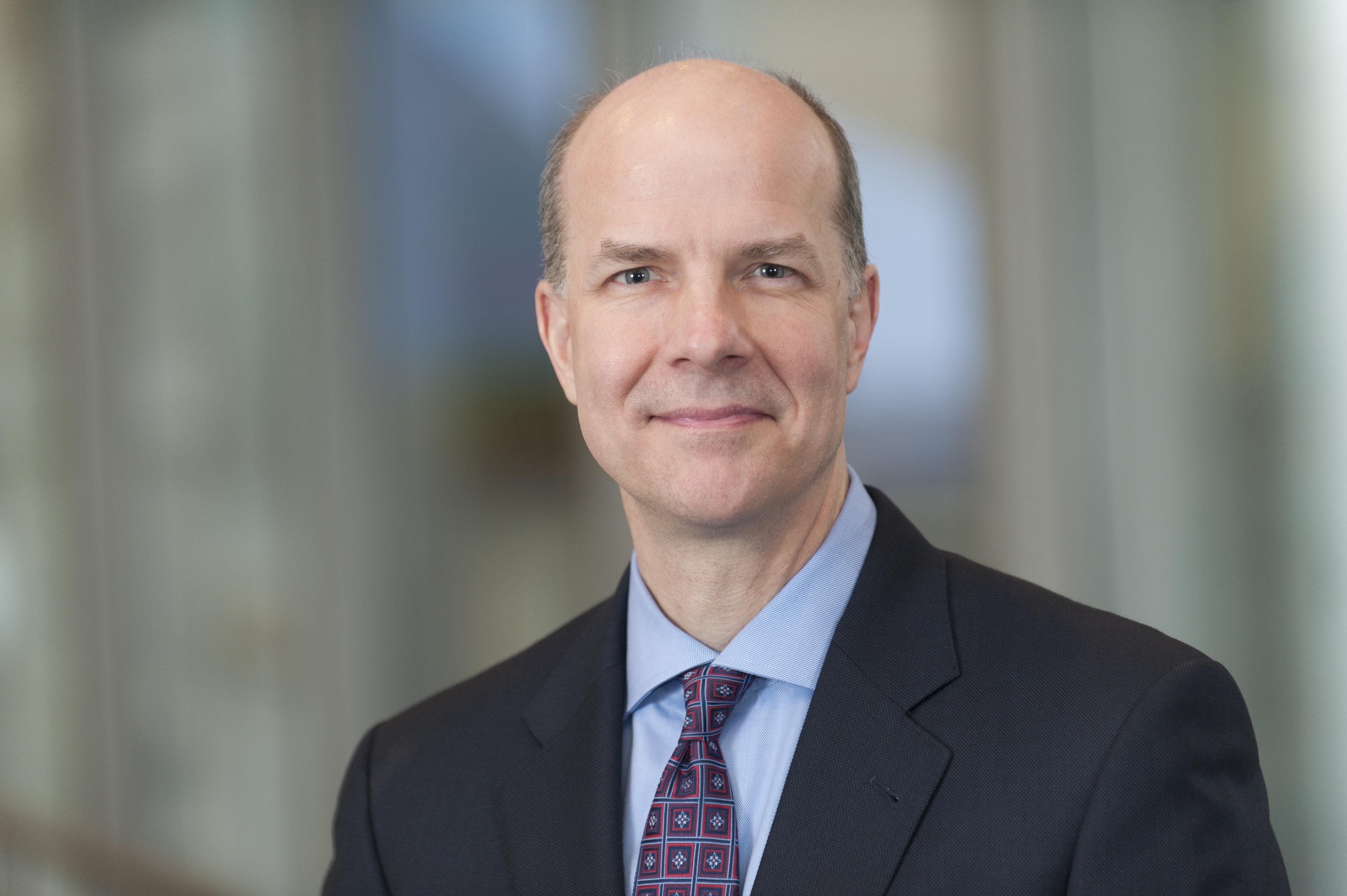 A man in a suit poses for a headshot. 