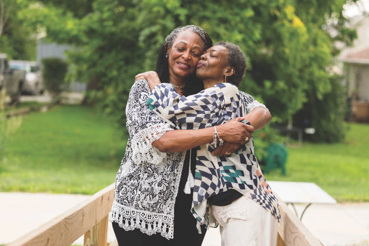 Kathy Lane hugs her sister outside on a summer day