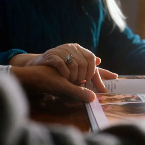 a close up shot of a woman's hand with a wedding ring over a man's hand.