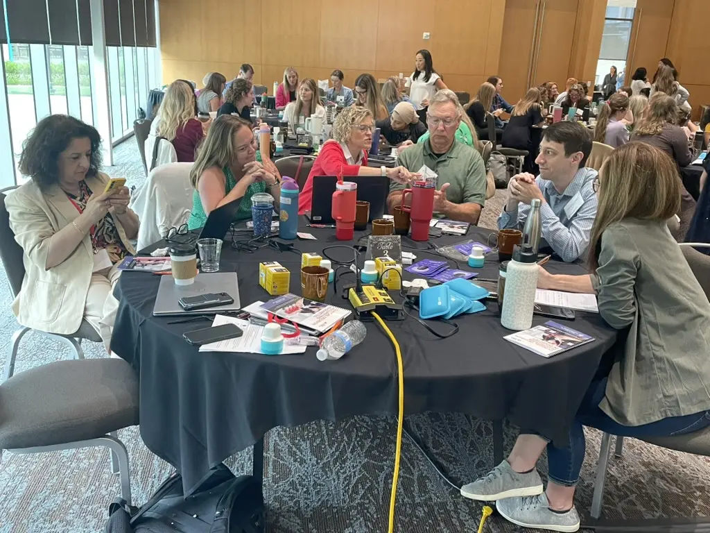 A table of people is shown learning how to use continuous glucose monitoring devices.