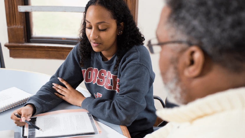 a student and mentor meet together and look at coursework
