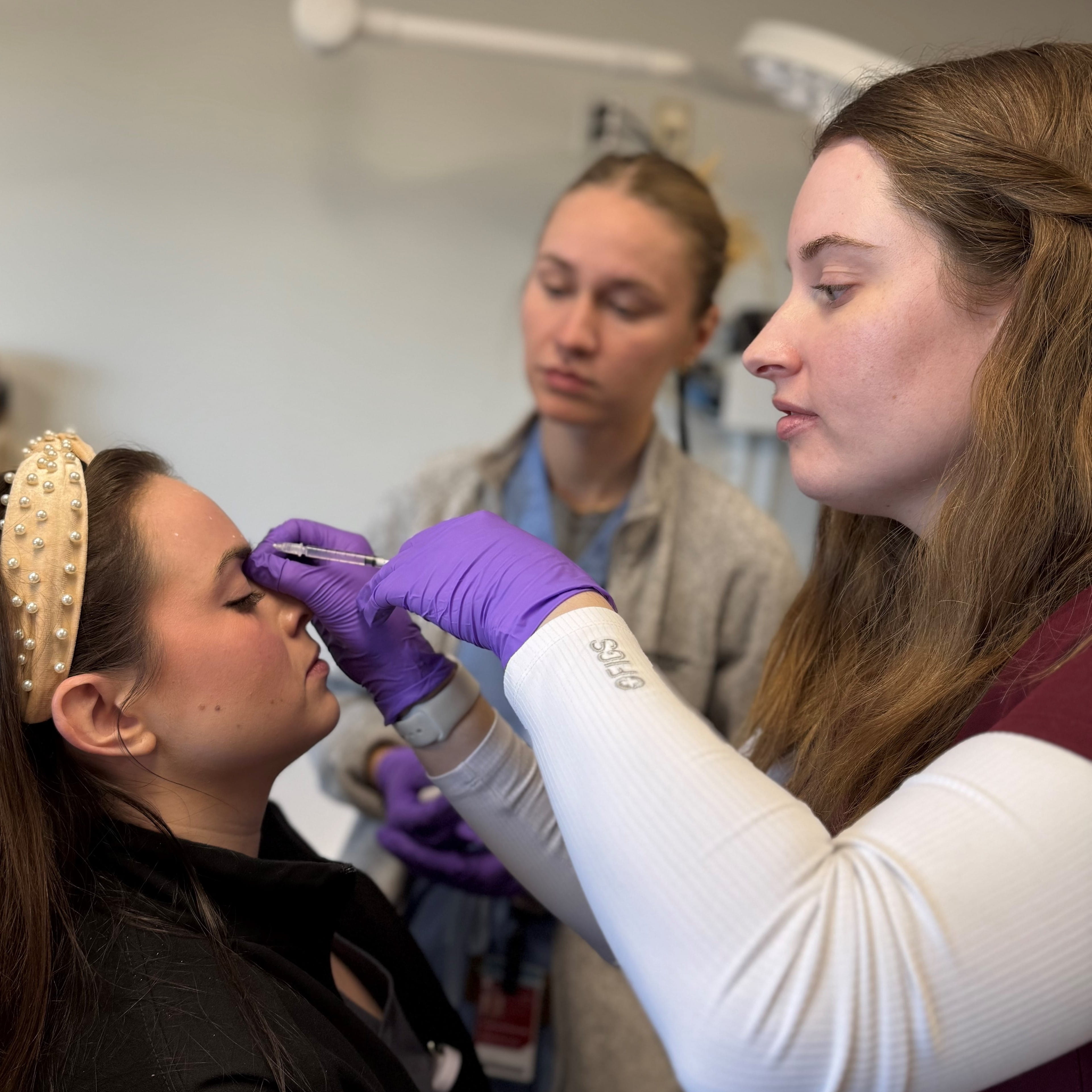 Dermatology Residents Anna Eden and Erica Aukerman preparing a patient for an injection