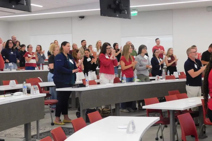 attendees in a conference room stand to applaud