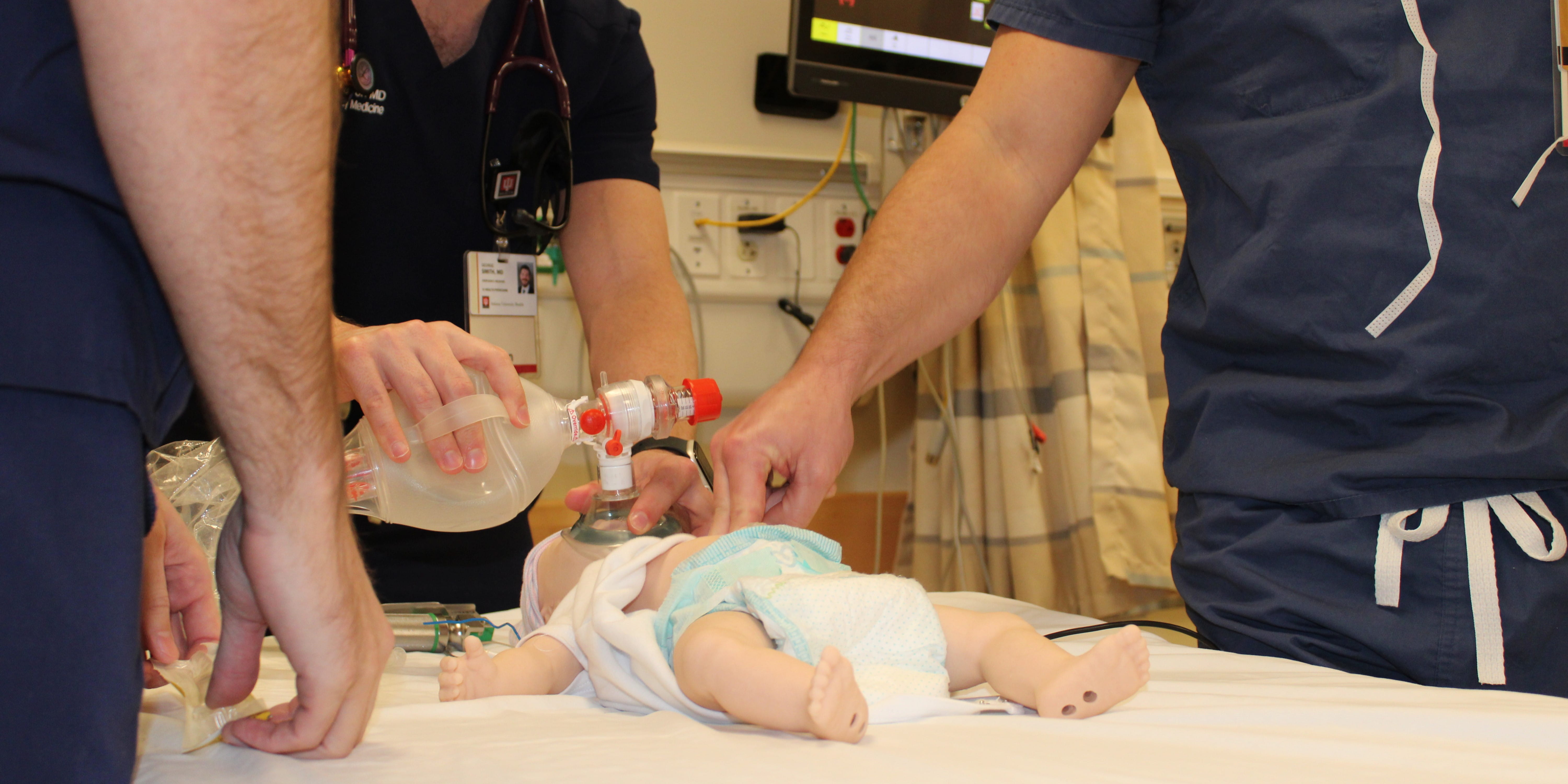 Physicians providing air to an infant patient mannequin