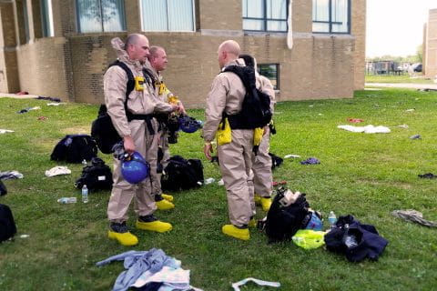 emergency responders dressed in tan jumpsuits wearing packs, special boots and helmets.