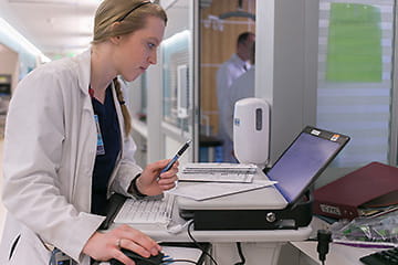 A fellow working on a computer in the hospital. 