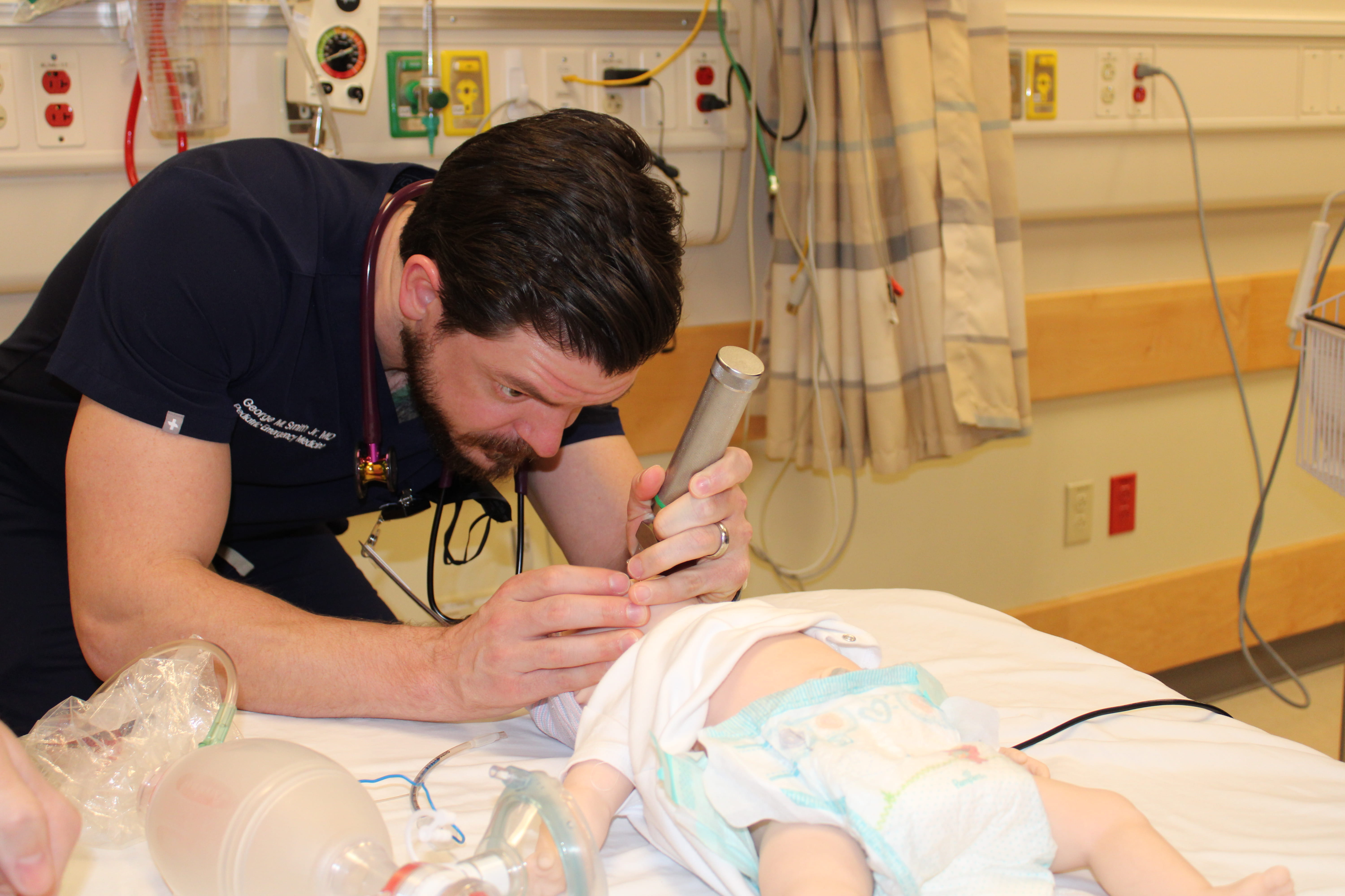 A PEM fellow performs a simulated intubation on a pediatric patient mannequin.