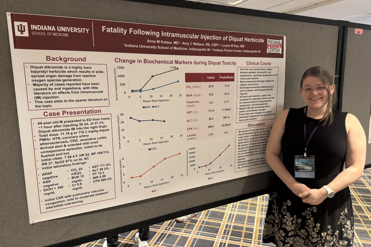 Anna Kolasa stands with her research poster at a conference presentation