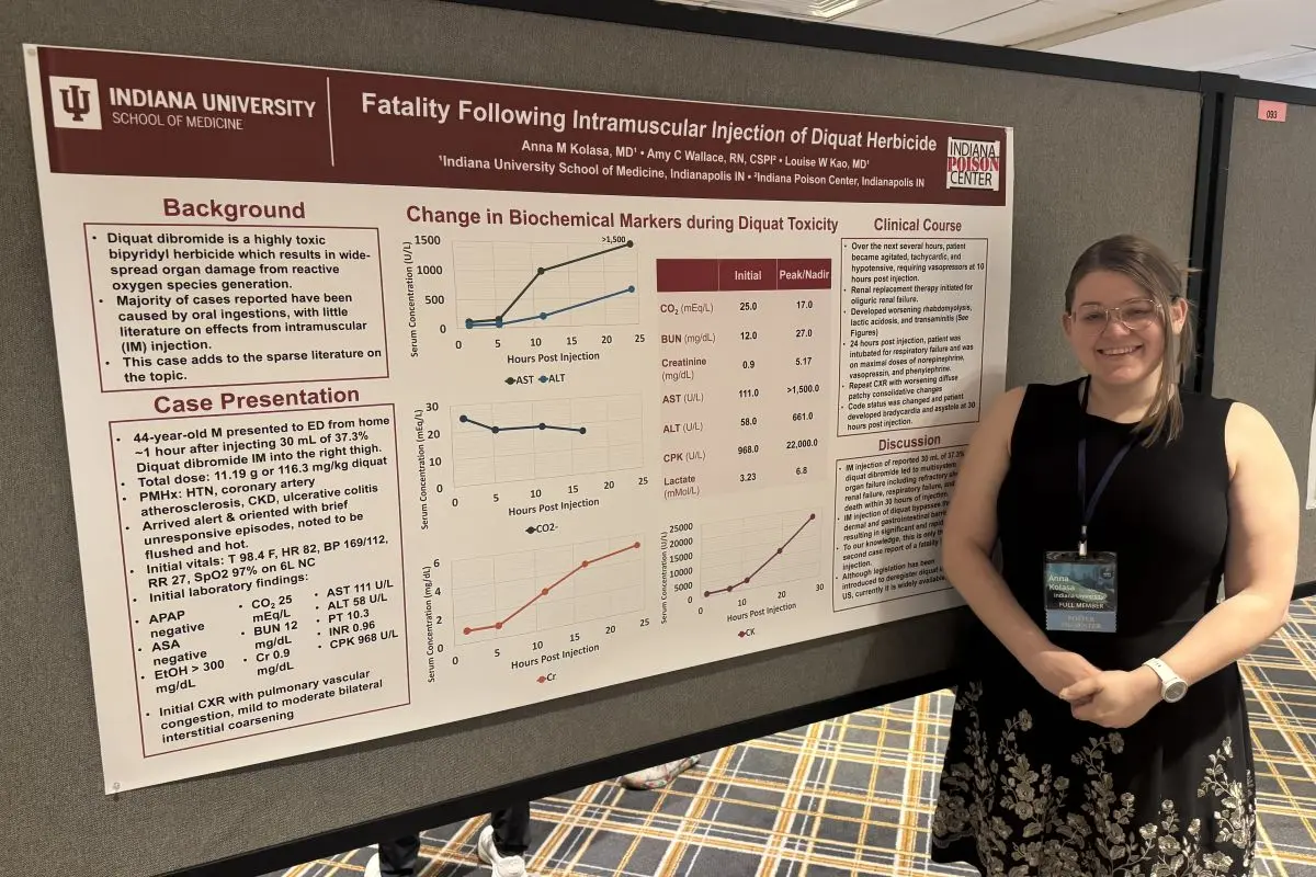 Anna Kolasa stands with her research poster at a conference presentation