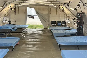 A medical tent set up with empty beds. 