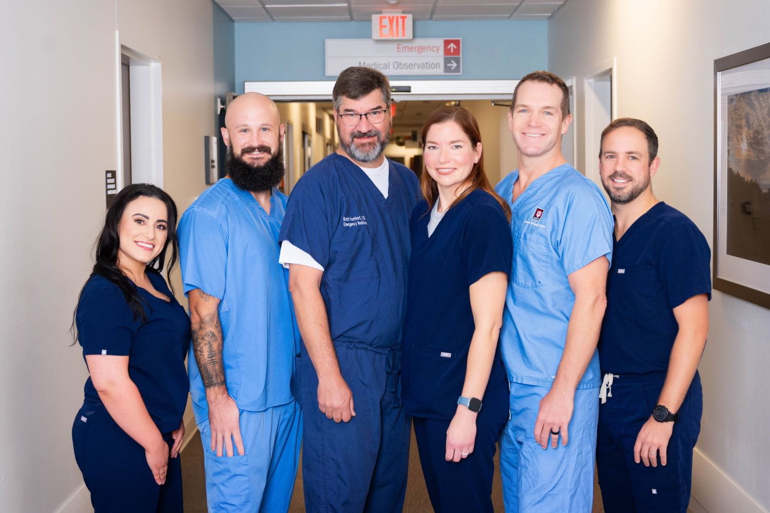 A group of physicians smiling in an emergency department hallway.