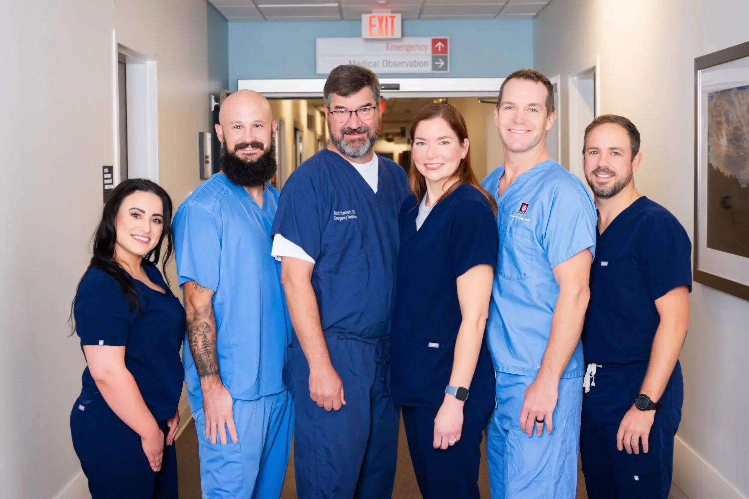 A group of physicians smiling in an emergency department hallway. 