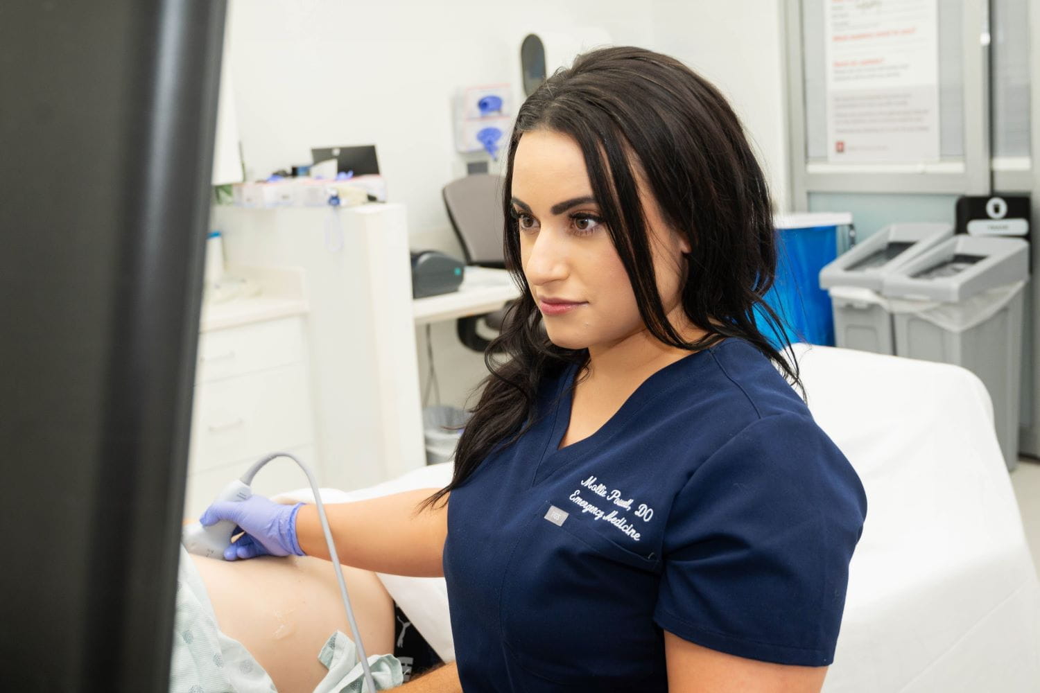 An individual performs ultrasound on a patient in the emergency department.