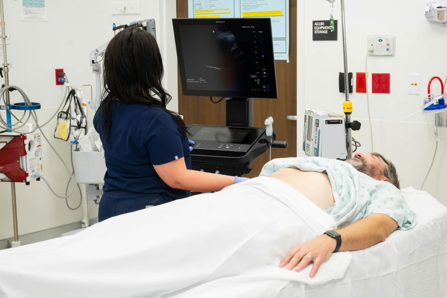 An individual performs ultrasound on a patient in the emergency department.