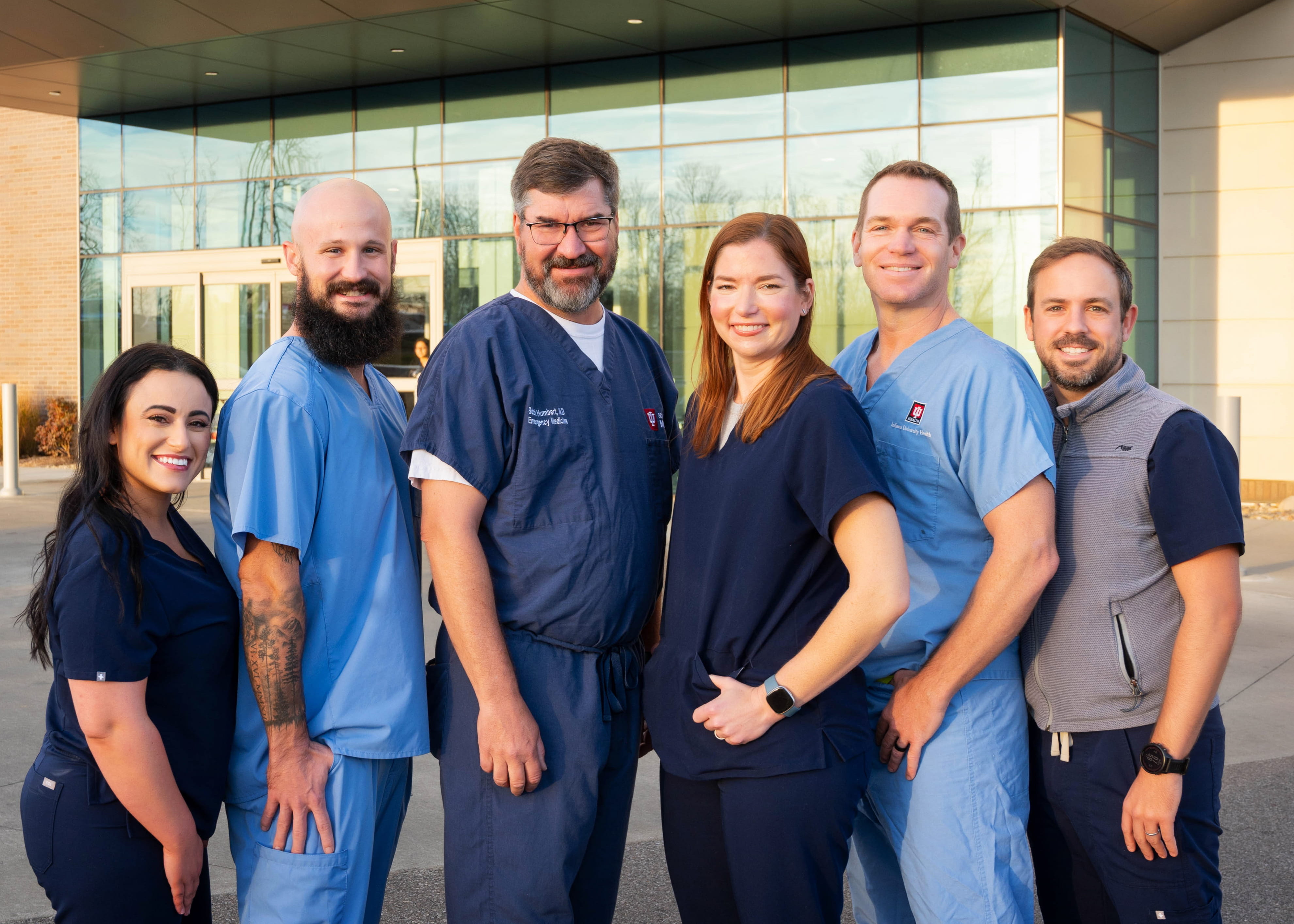 Six faculty members smile in front of the emergency department outside.. 