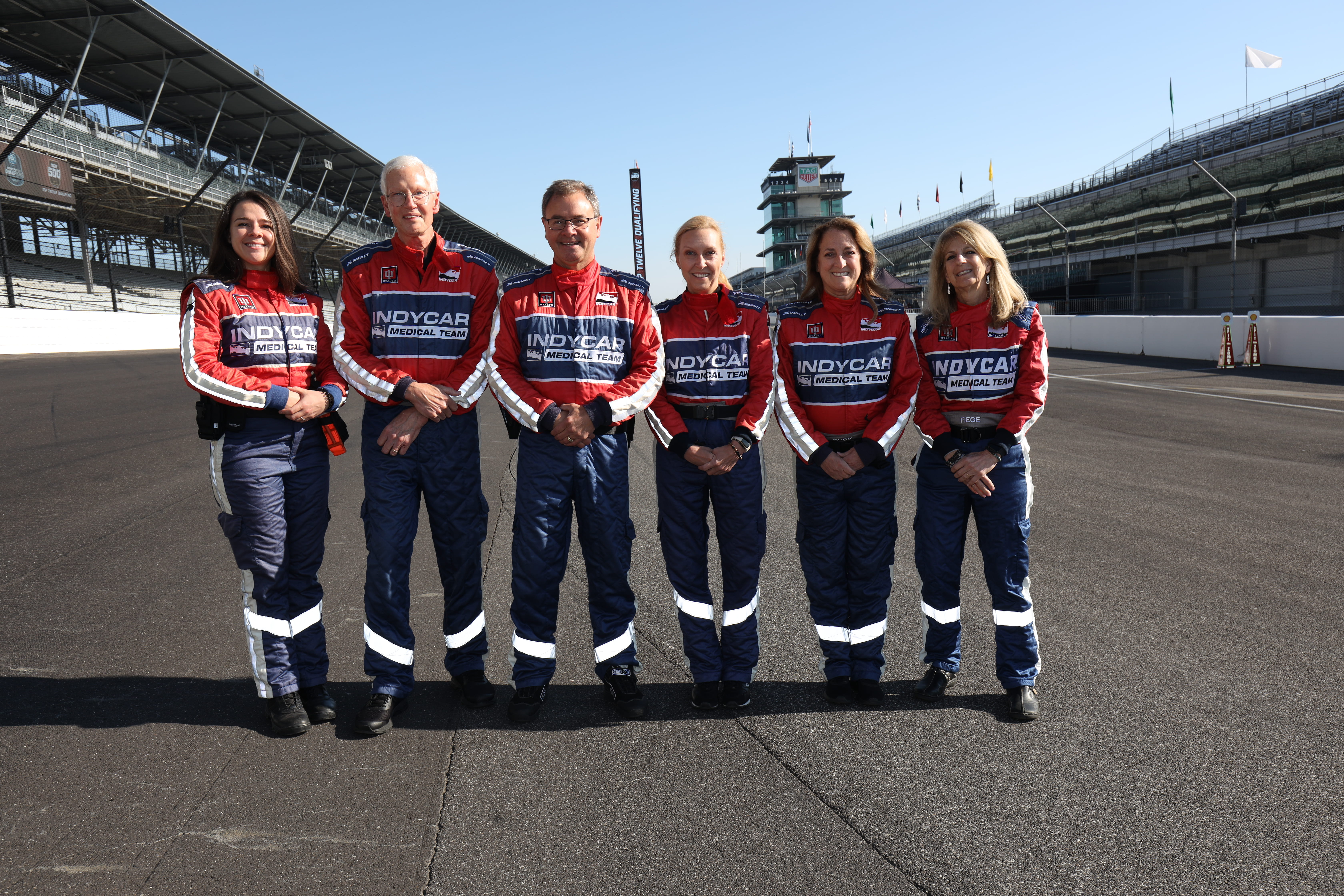 Fellowship faculty pose for a group photo on the race track. 
