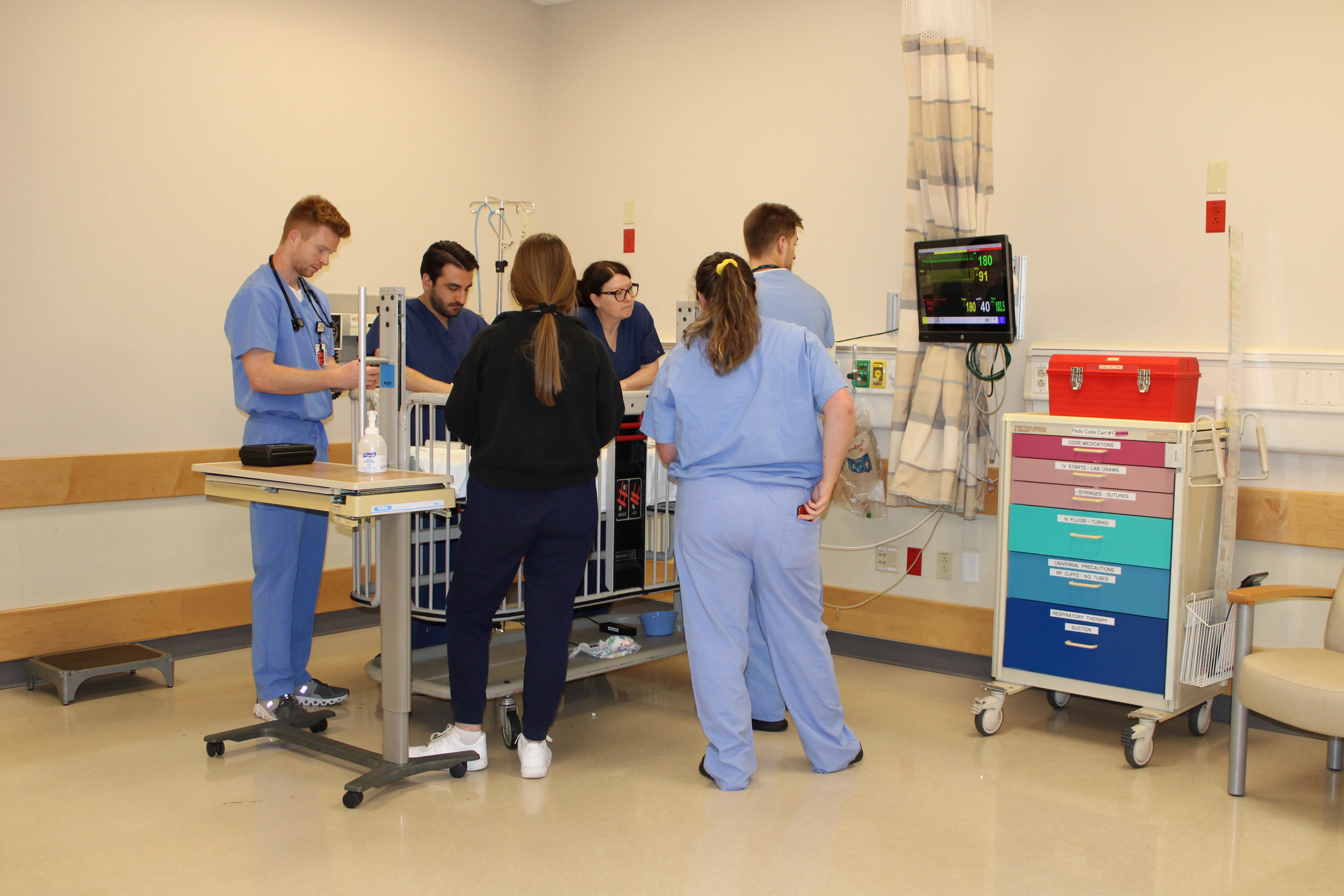 Medical students surround a baby mannequin patient during a pediatric emergency medicine simulation case. 
