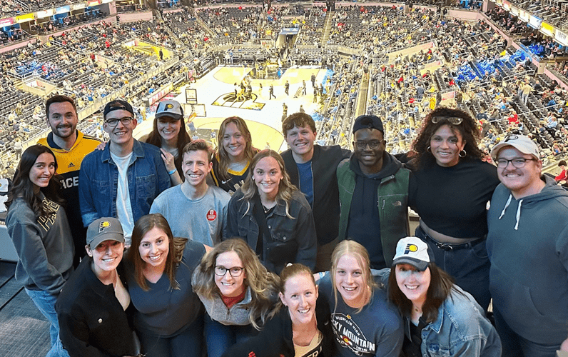 A group of smiling residents take a group photo at a Pacers basketball game.