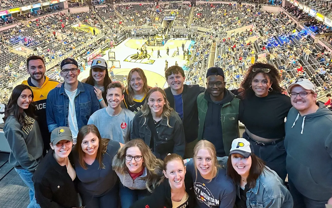 A group of smiling residents take a group photo at a Pacers basketball game.