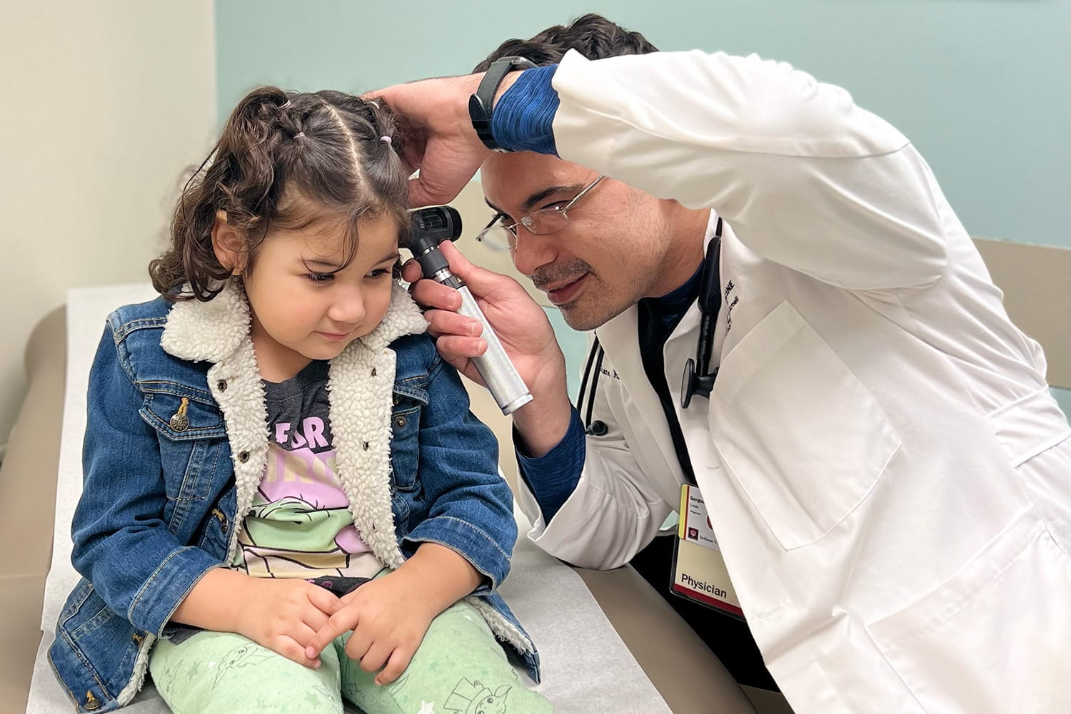 a physician looks inside a child's ear during an exam