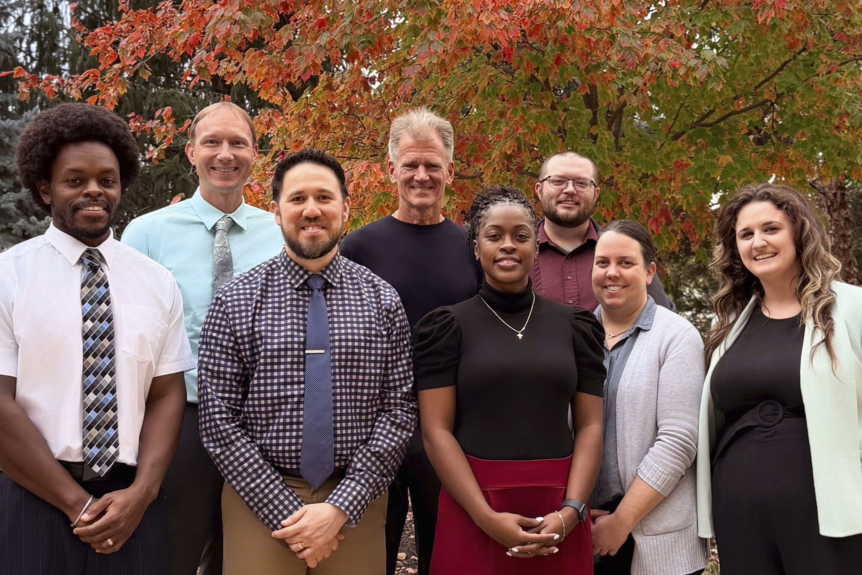 eight diverse faculty members outside on a sunny fall day