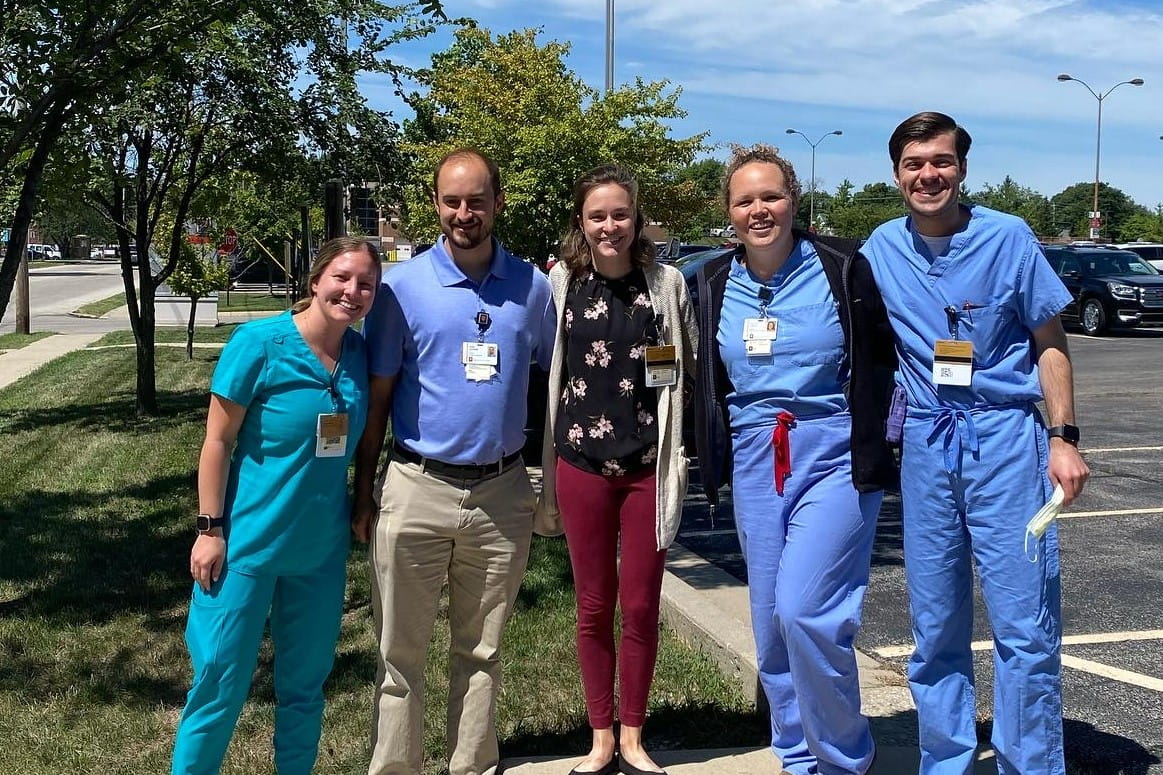5 residents pose for a group photo outside on a sunny day