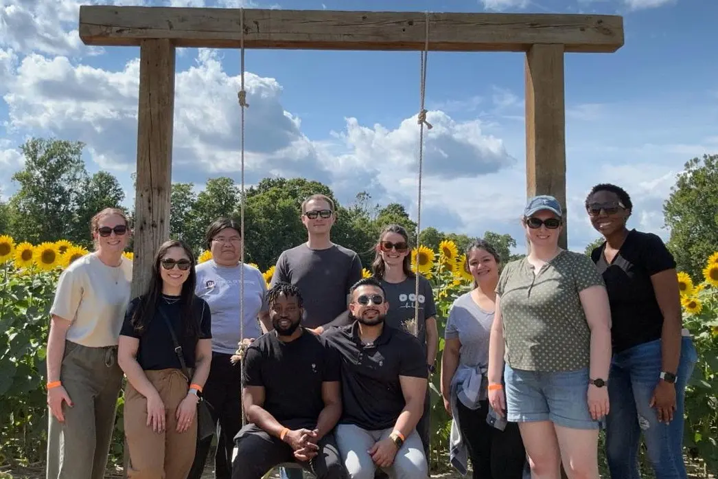 Residents sit and stand together outside on a sunny day surrounded by sunflowers