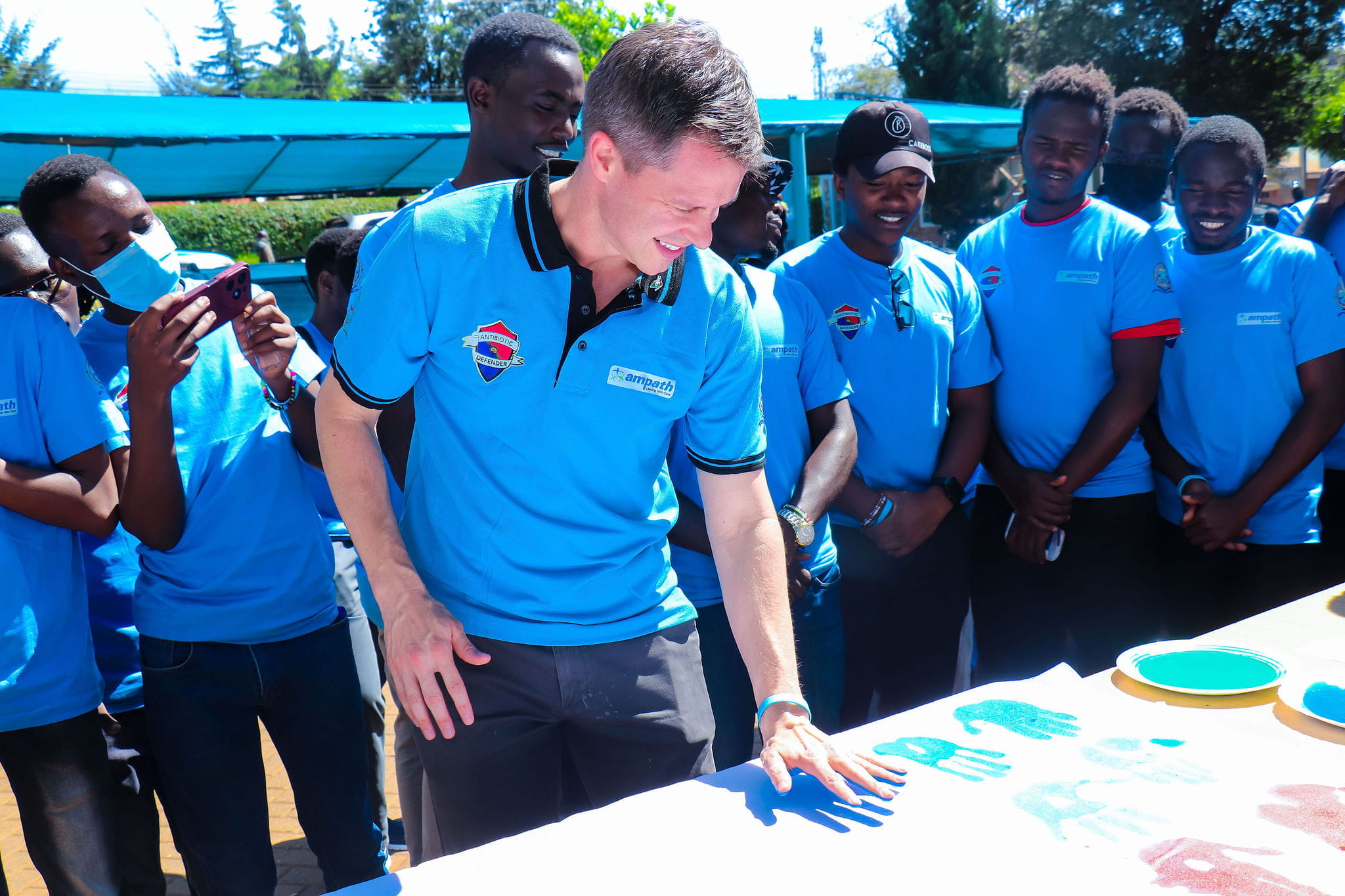 Jack Schneider, MD, places a painted handprint on a canvas during a trip with AMPATH to Kenya. 