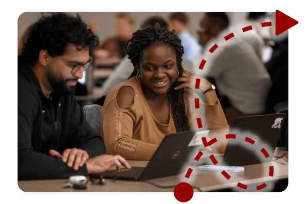 two students work together on a laptop during class