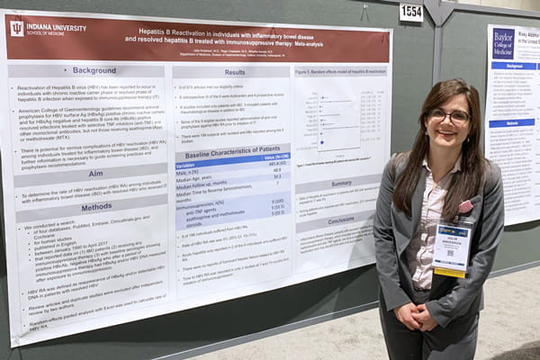 a resident stands in front of her poster presentation