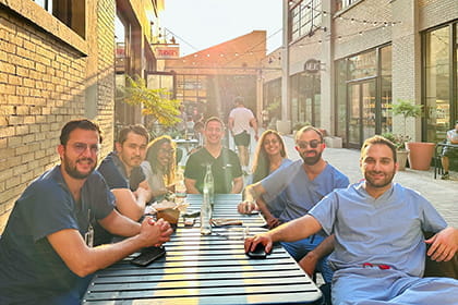 Photo of our group of fellows sitting outside a taco restaurant smiling.