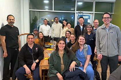 A blend of gastroenterology fellows and faculty out at a restaurant smiling after enjoying dinner together.