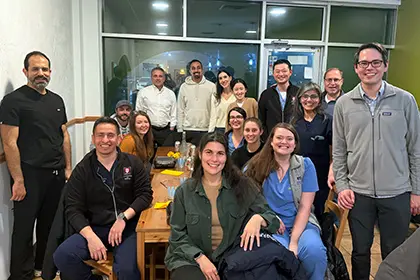 A blend of gastroenterology fellows and faculty out at a restaurant smiling after enjoying dinner together.