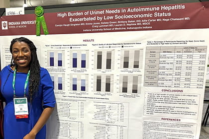 Photo of Dr. Nephew smiling in front of her research poster at AASLD 2023.