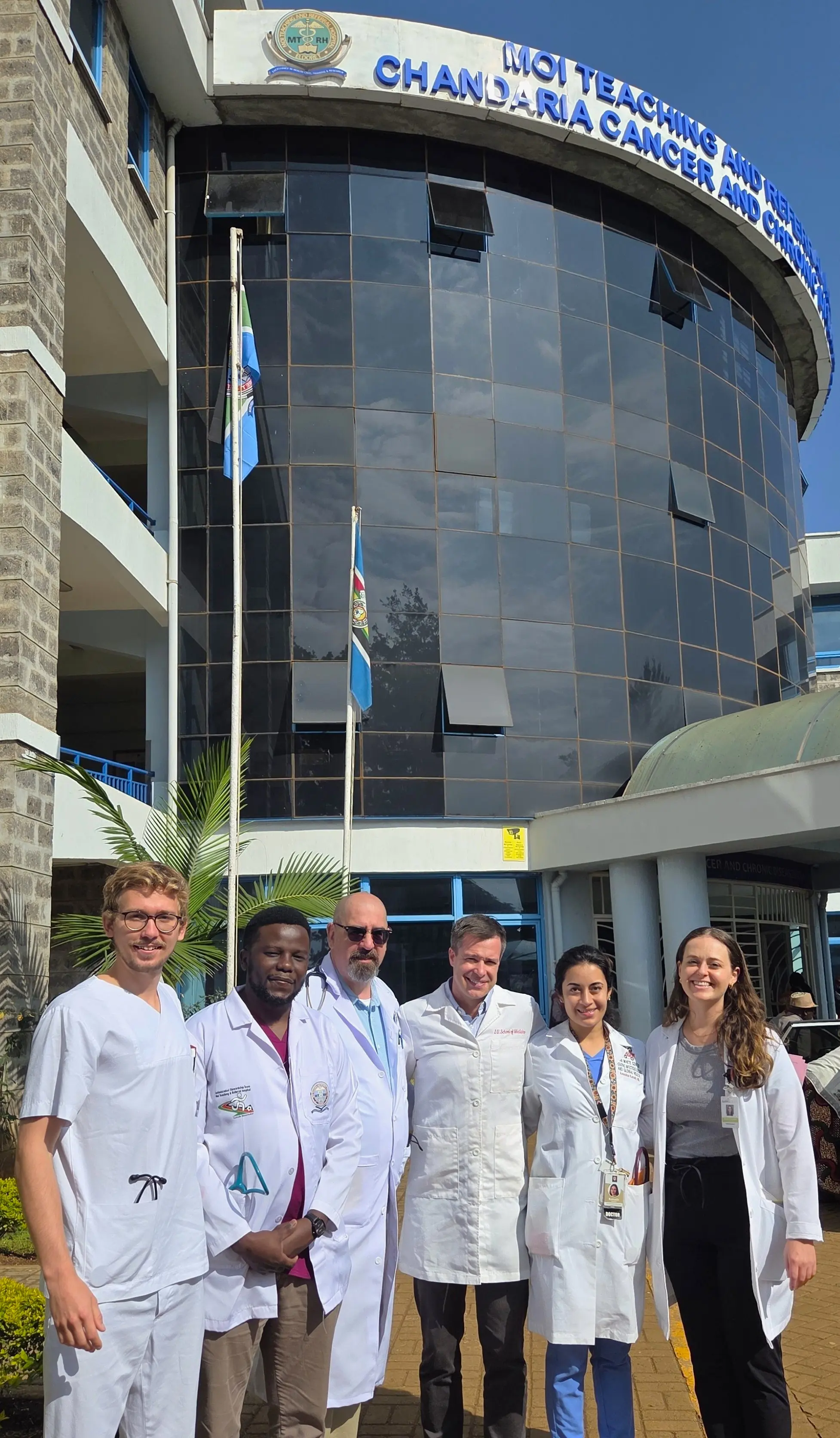 a group of physicians outside the Moi hospital on a bright sunny day