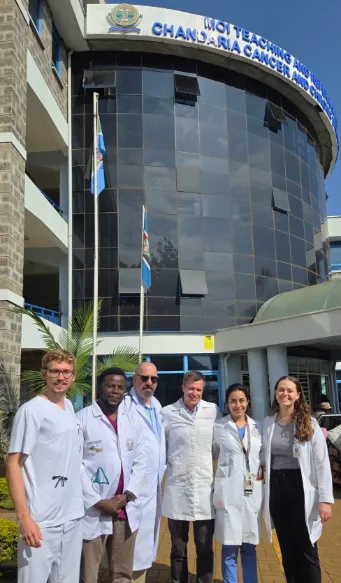 a group of physicians outside the Moi hospital on a bright sunny day