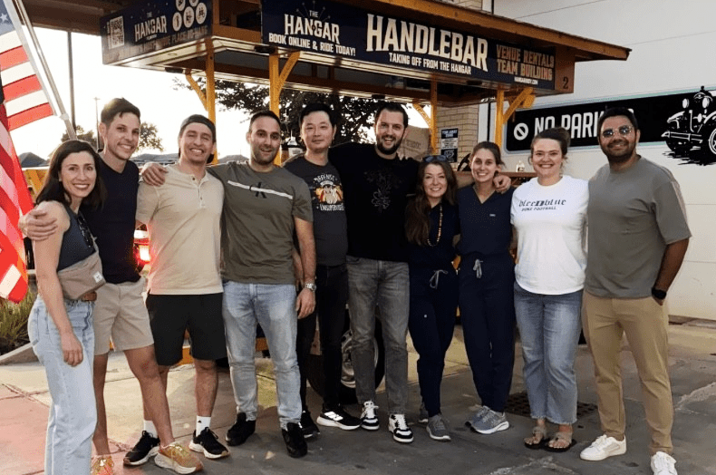 Photo of our IU Gastro fellows smiling in front of the Handlebar from the Hanger cart.