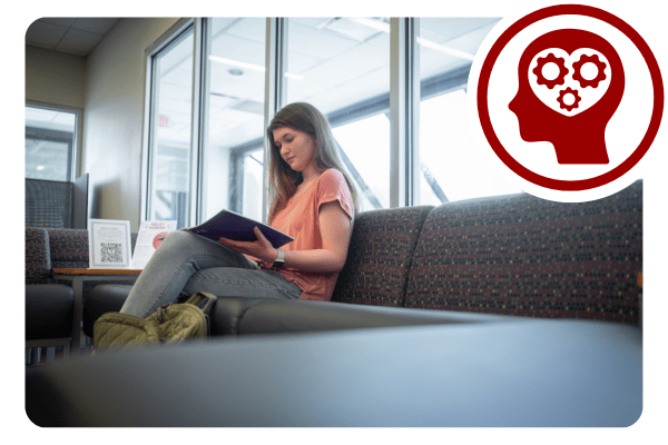A female student reads a book while sitting on a sofa