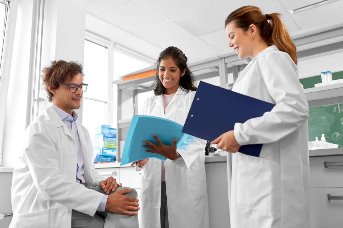 Three physicians in white coats discuss case notes
