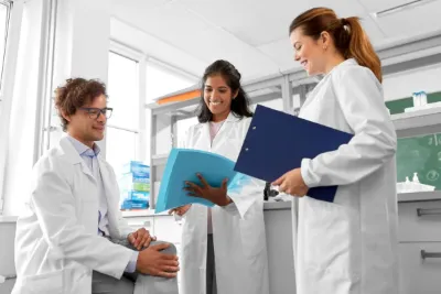 Three physicians in white coats discuss case notes