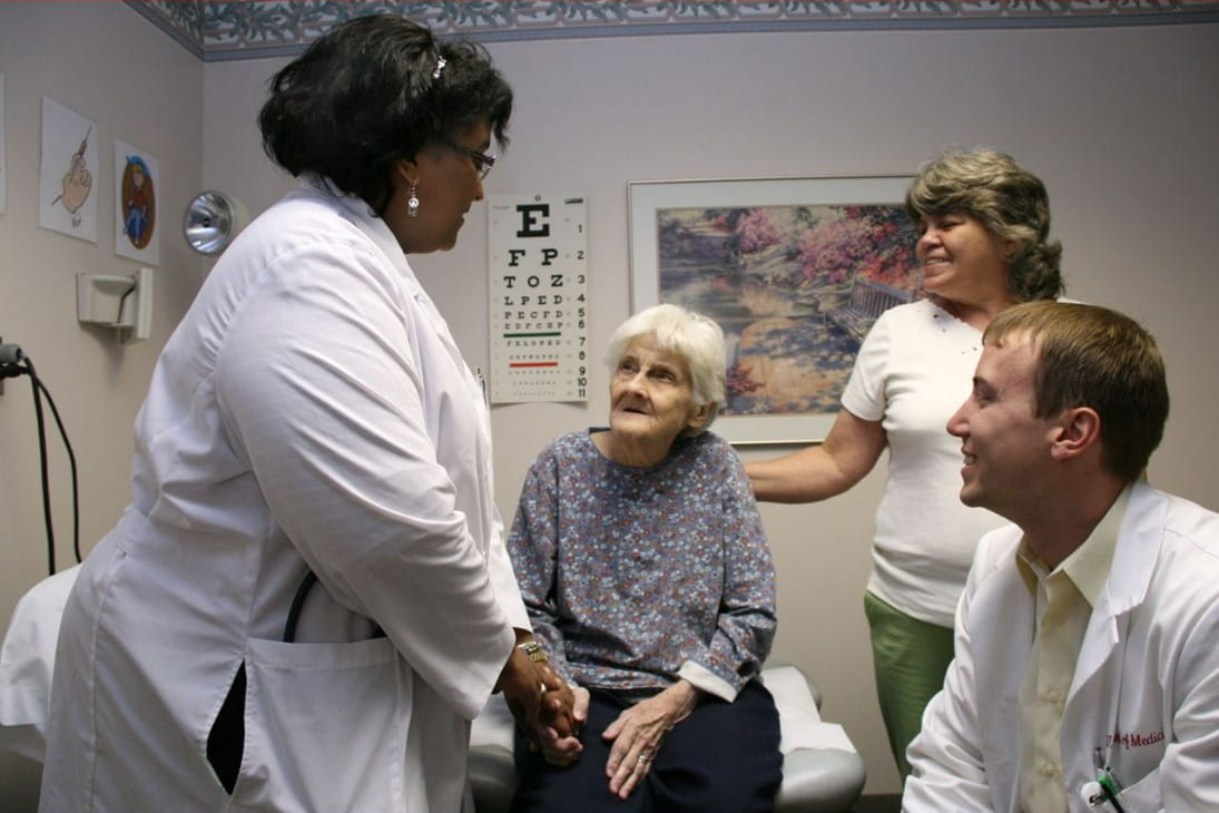 Dr. Westmoreland holds the hand of an elderly patient in an exam room