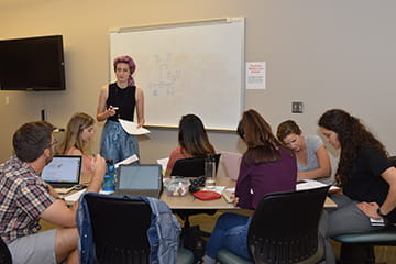 an instructor at the front of a classroom full of students
