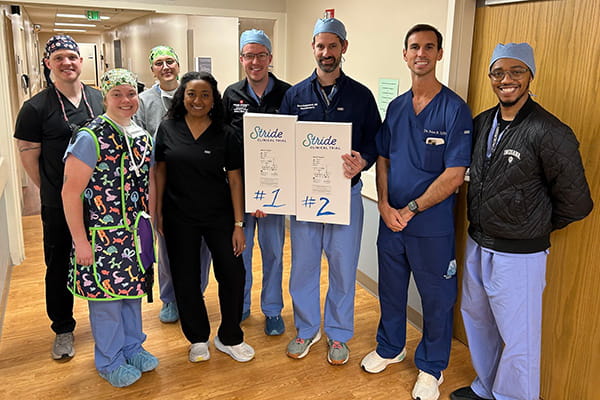 Dr. Bohnstedt with the IU Health team holding a sign celebrating the first STRIDE patient surgeries.