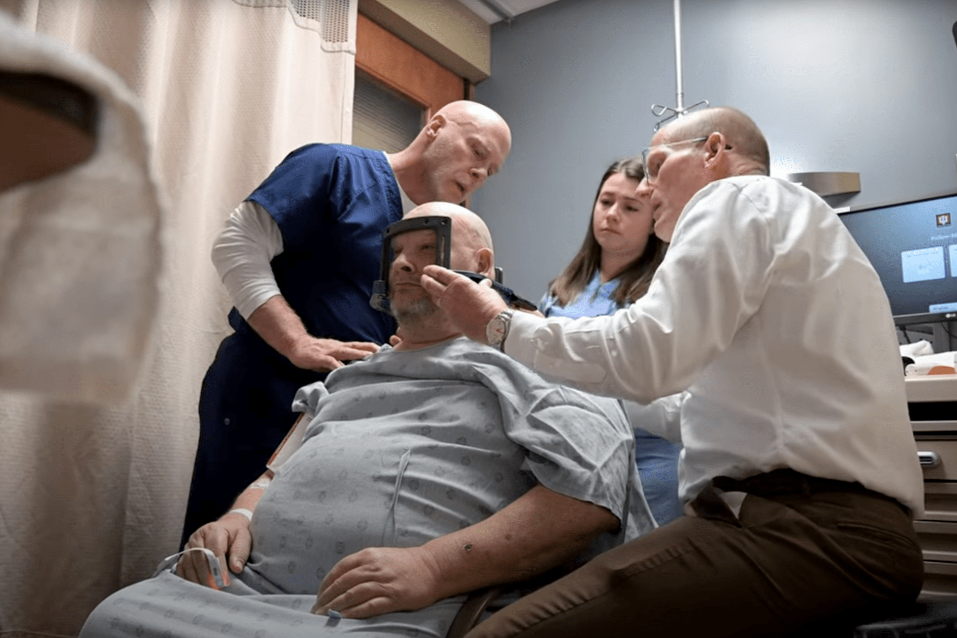 Three physicians examining a patient in a hospital room