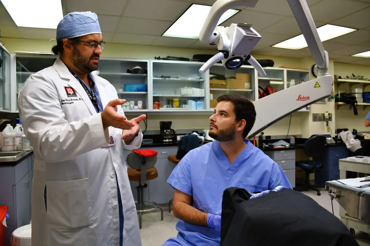 Dr. Almeida talking with a student in the Microneurosurgery Laboratory