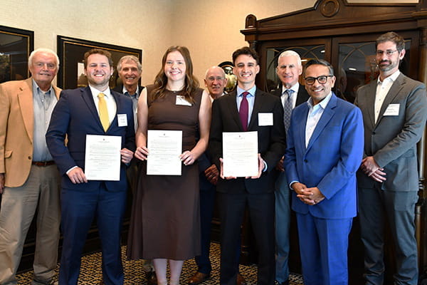 Group photo at an awards luncheon with three students holding certificates