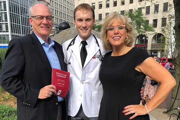 A medical student with his parents at a white coat ceremony