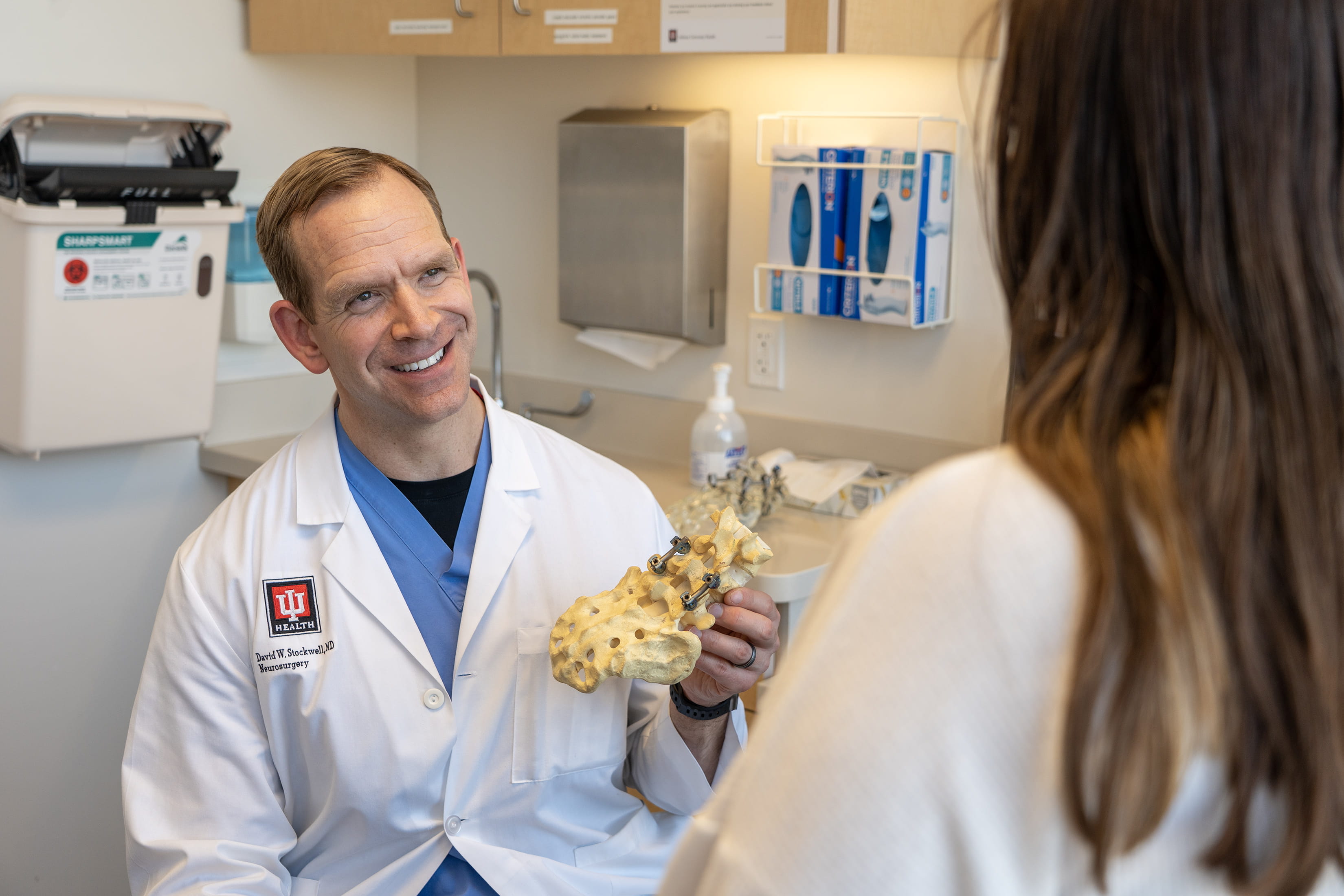 A doctor shows a spine model to a patient in clinc