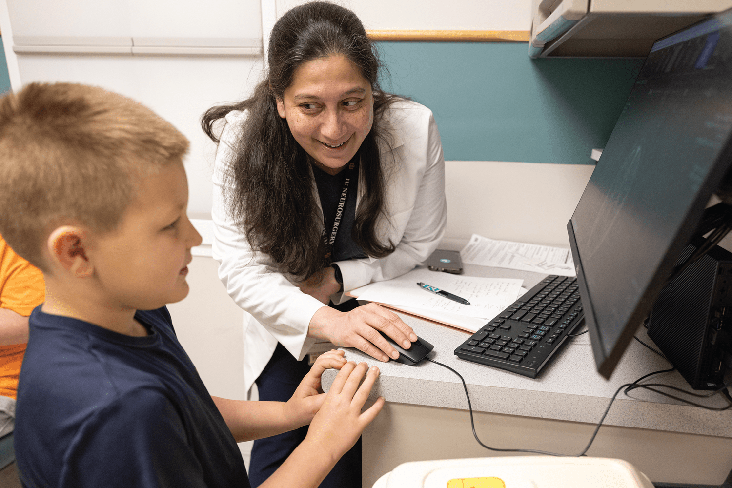 a neurosurgeon talks with a child in the clinic