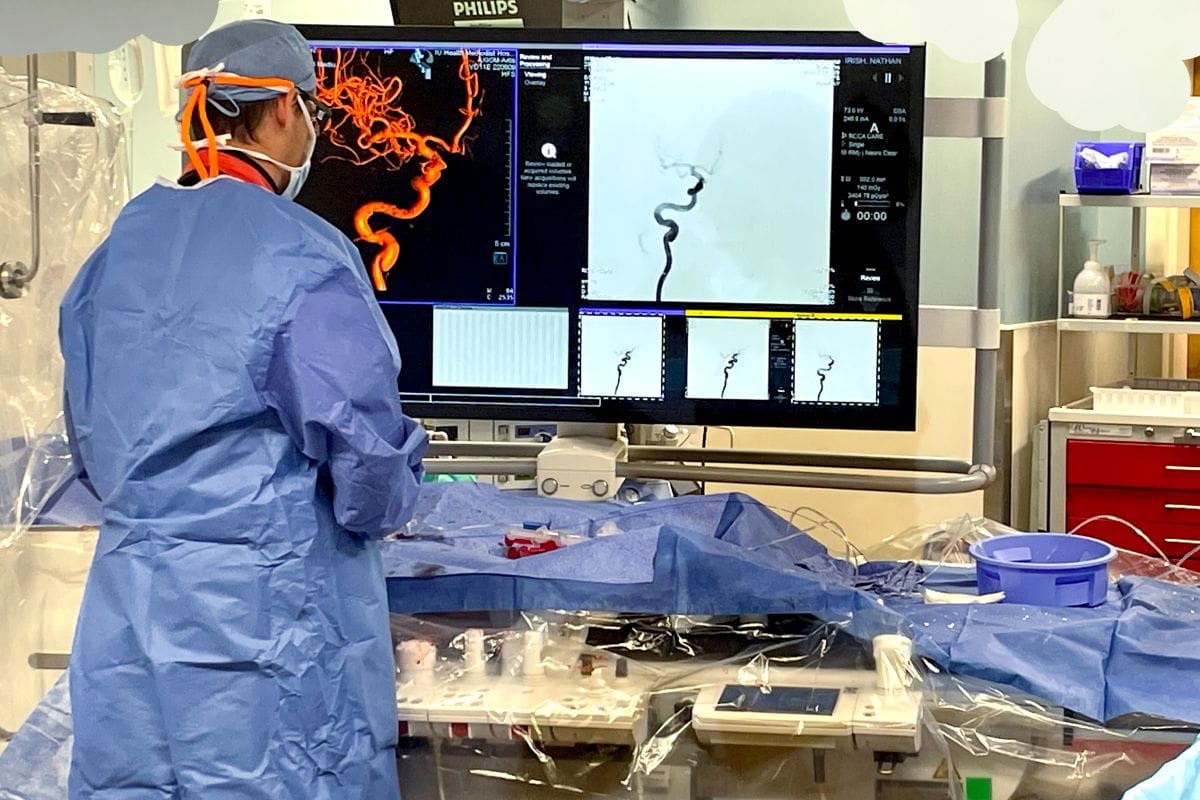 a neurosurgeon stands near a computer in the OR